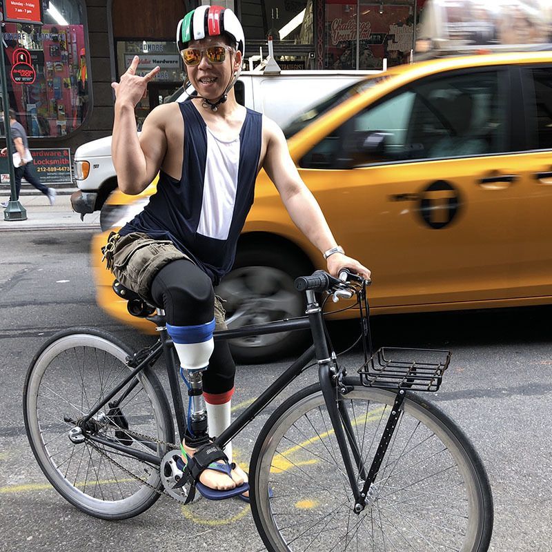 A man with a prosthetic leg is riding a bike on the street