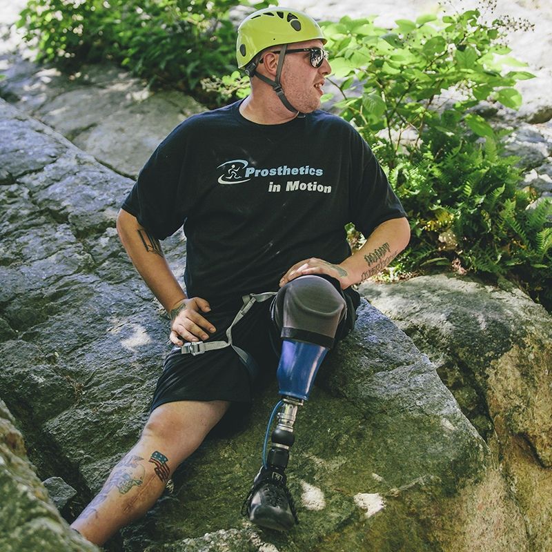 A man with a prosthetic leg is sitting on a rock