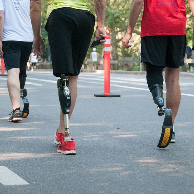 Three men with prosthetic legs are walking down a street