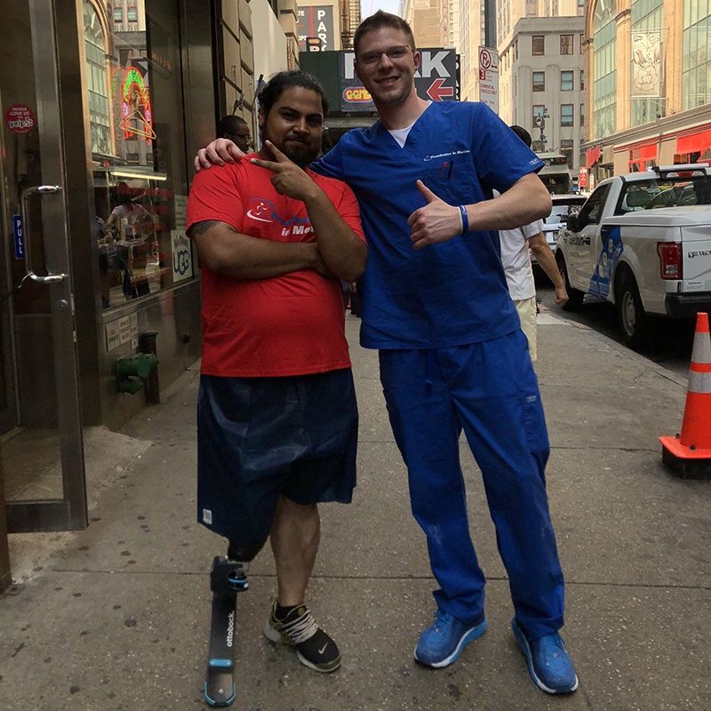 A man with a prosthetic leg stands next to a man in scrubs