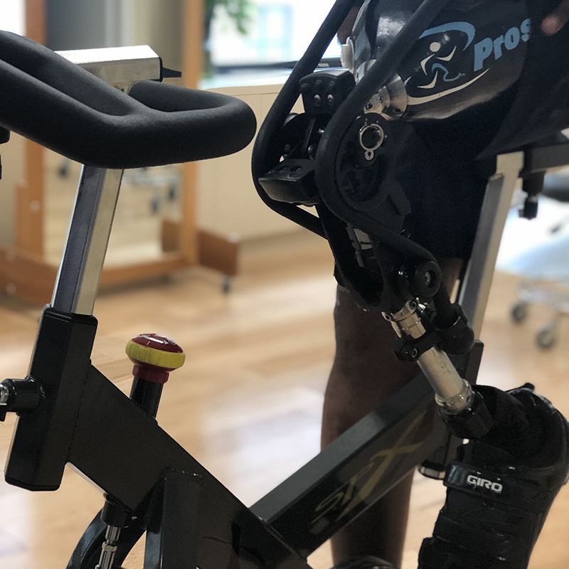 A person wearing a prosthetic leg is riding an exercise bike