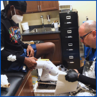 A man wearing a mask is getting a cast on his leg