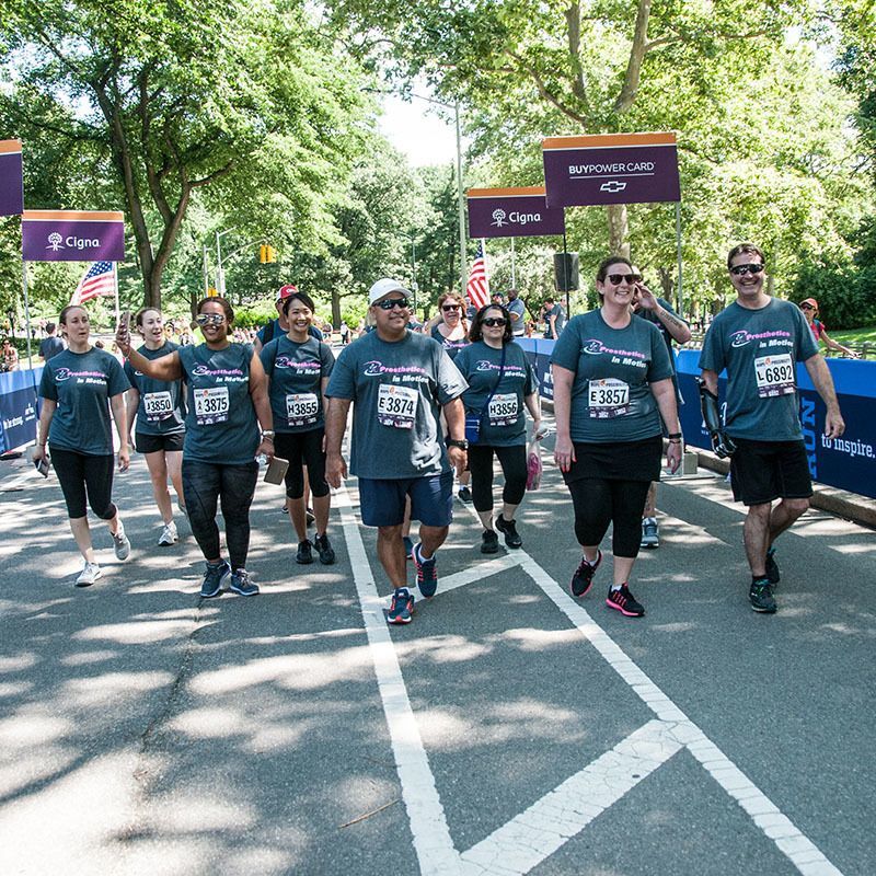 A group of amputees walking down a street wearing shirts with numbers on them