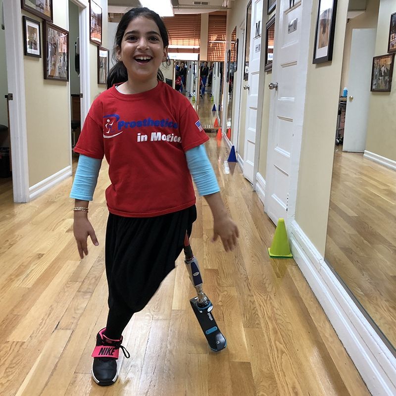 A girl with a prosthetic leg is walking down a hallway