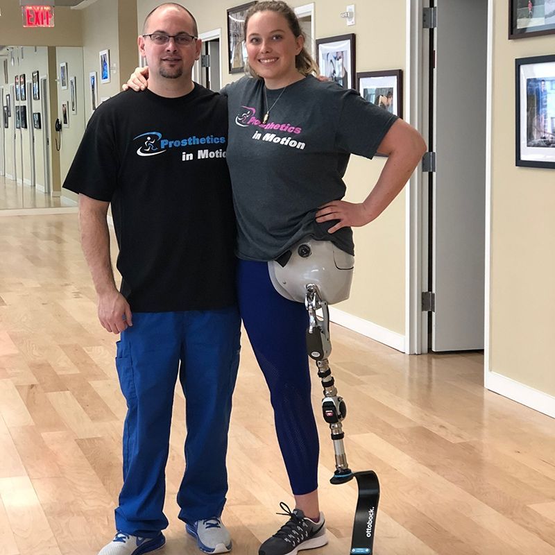 A woman with a prosthetic leg stands next to a man wearing a shirt that says prosthetics in motion