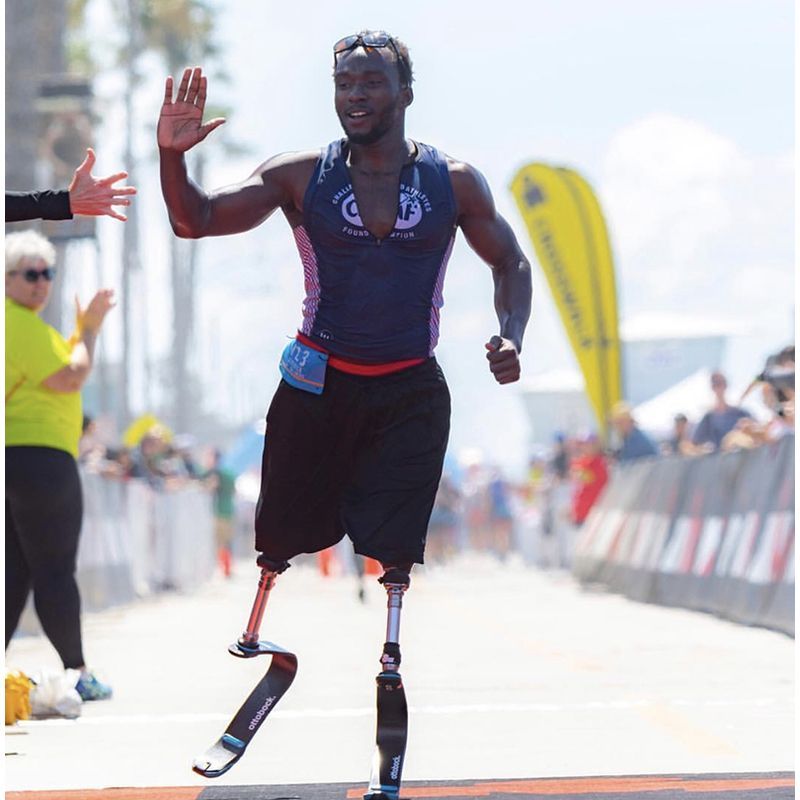 A man with prosthetic legs is running down a street