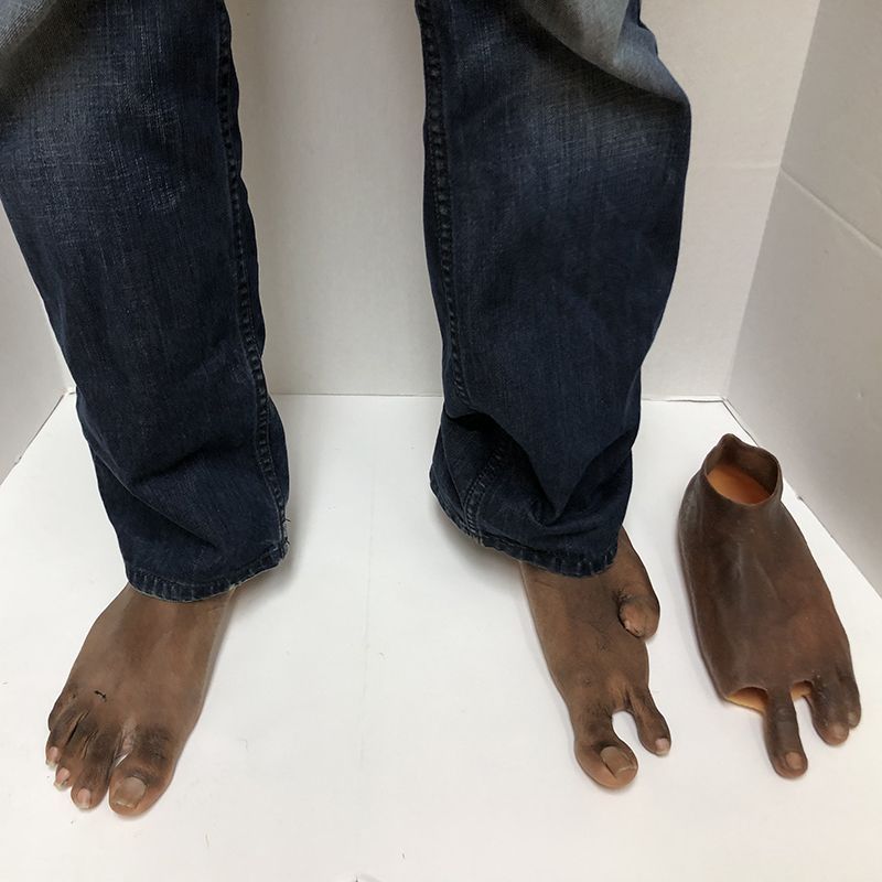 A pair of feet and a pair of shoes on a white surface