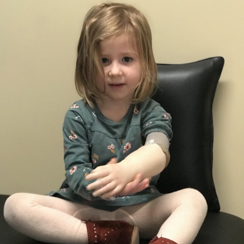 A little girl is sitting on a chair with her legs crossed
