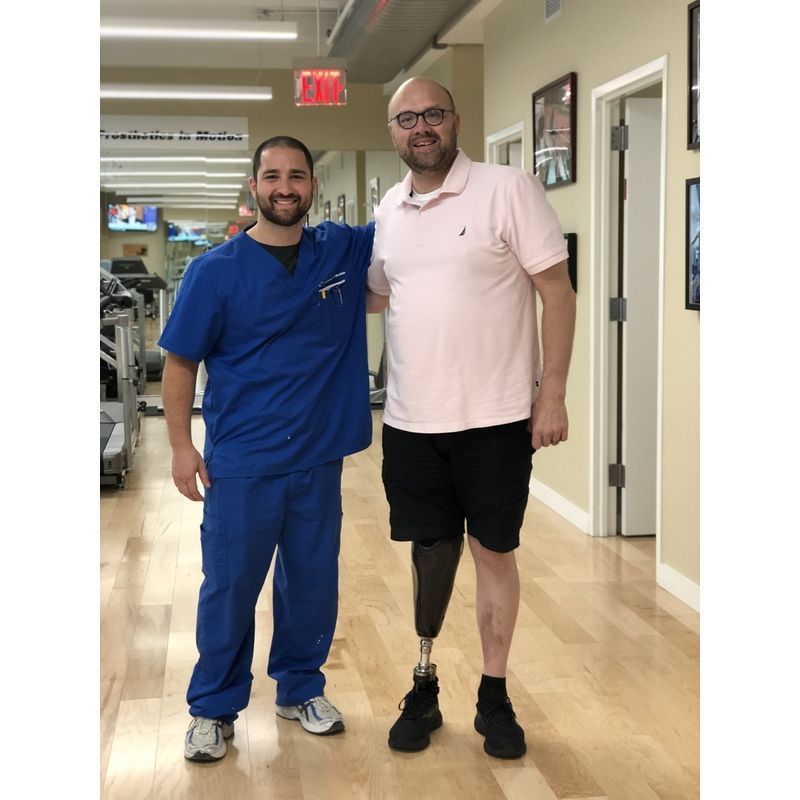A man with a prosthetic leg is standing next to a nurse