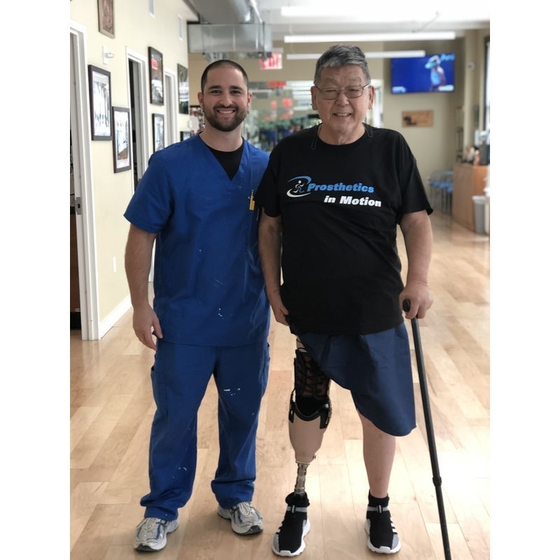 A man with a prosthetic leg is standing next to a nurse.