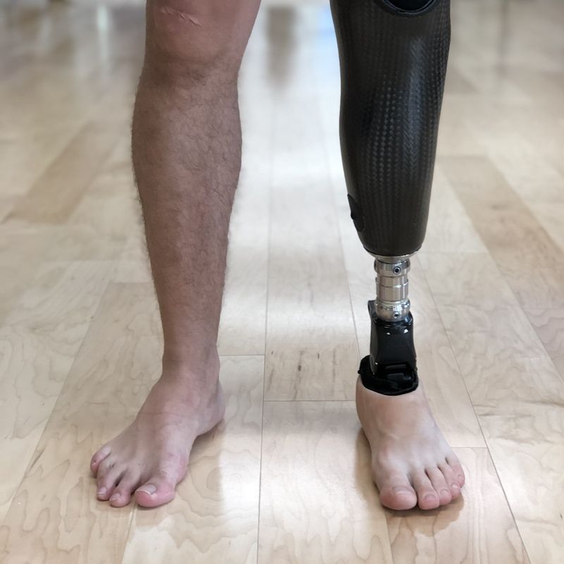 A man with a prosthetic leg standing on a wooden floor