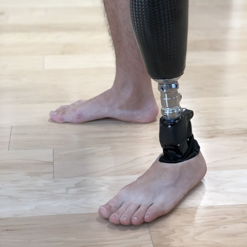 A man with a prosthetic leg is standing on a wooden floor