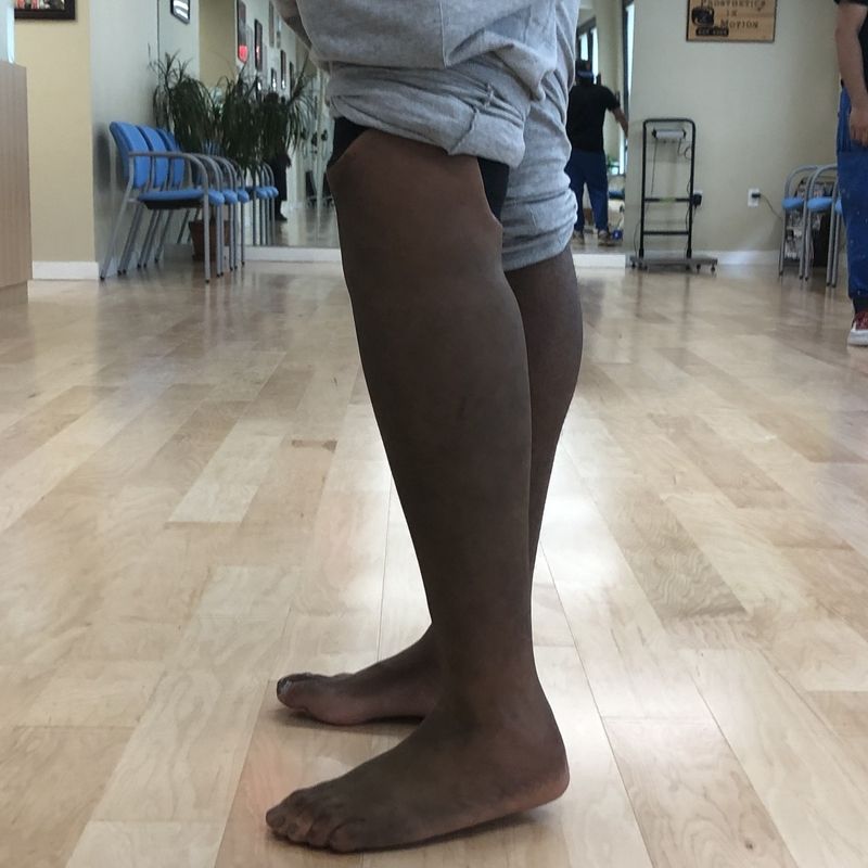 A person standing on a wooden floor with their legs crossed