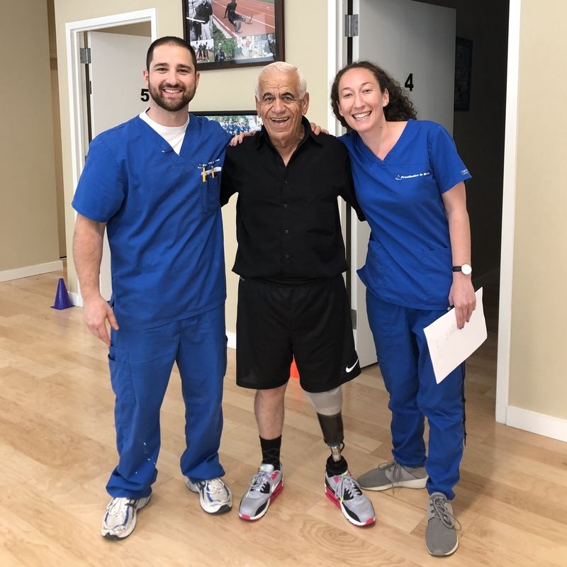 A man with a prosthetic leg poses for a picture with two nurses