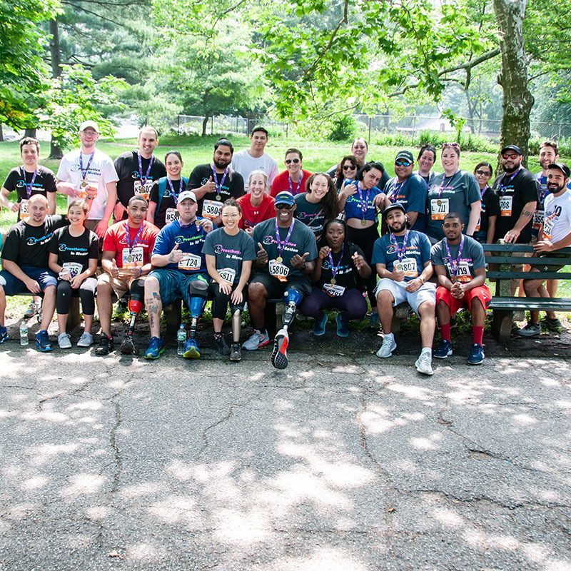 A group of amputees are posing for a picture in a park.