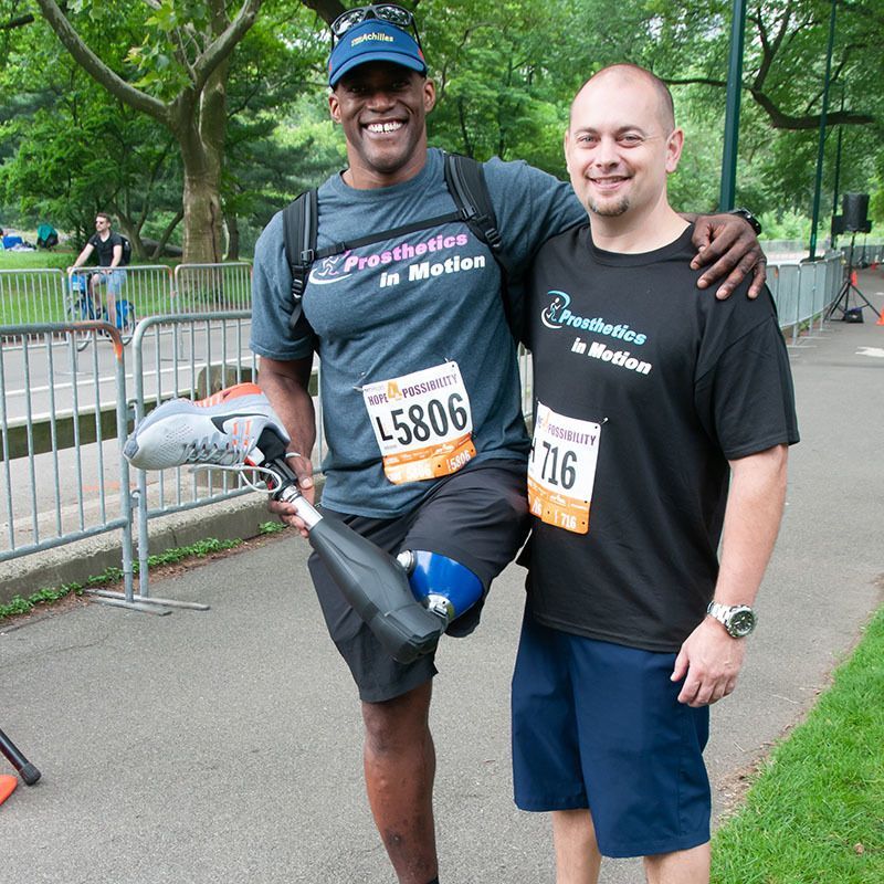 A man with a prosthetic leg is standing next to another man