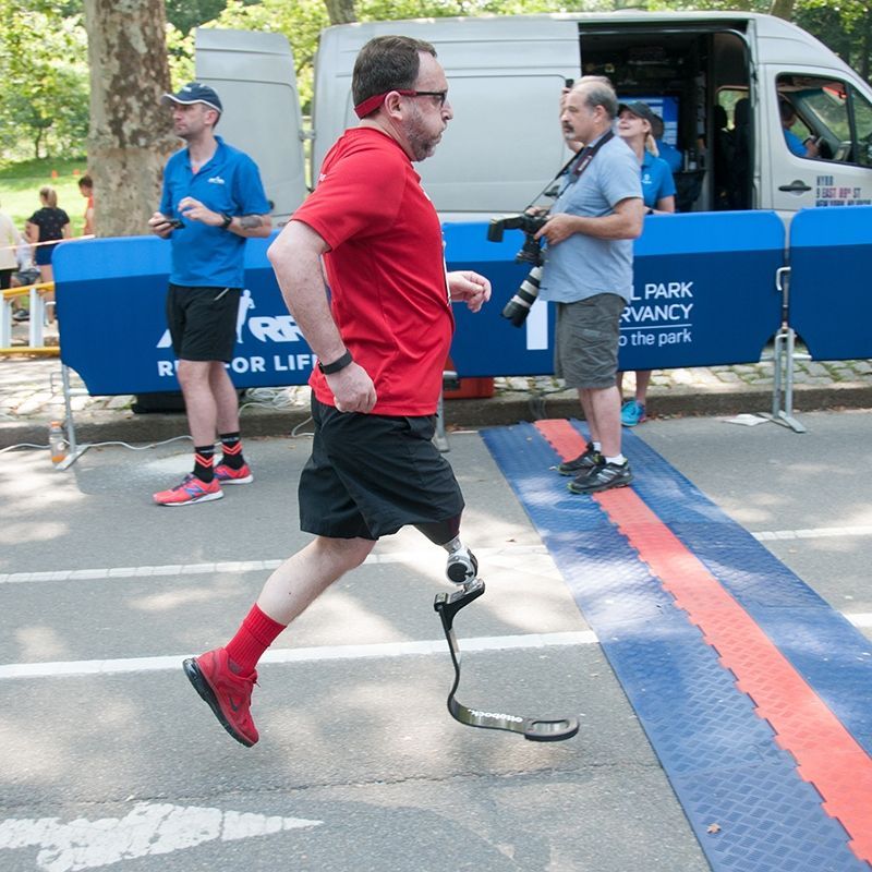 A man with a prosthetic leg is running down the street