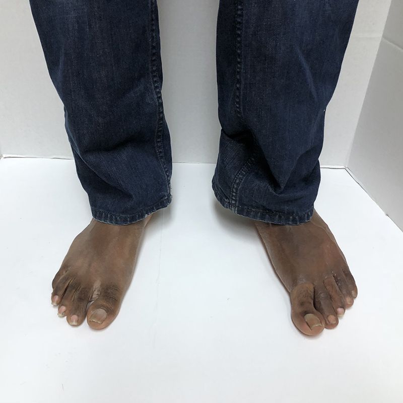 A pair of bare feet wearing blue jeans