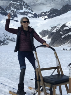 A woman is standing next to a sled in the snow