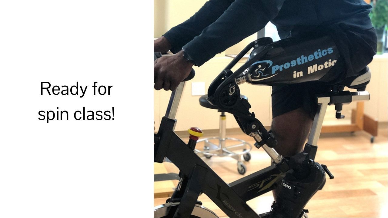 A man is riding an exercise bike wearing a prosthetic leg.