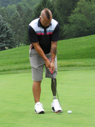 A man with a prosthetic leg is putting on a golf course