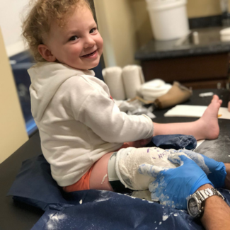 A little boy smiling at his pediatric leg casting appointment
