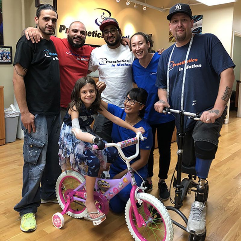 A group of people posing for a picture with a little girl on a pink bike