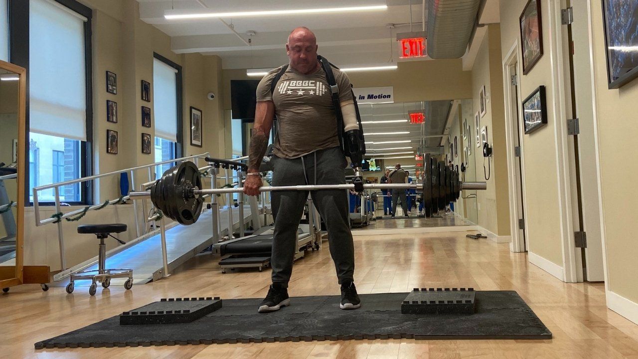A man wearing a below the elbow vacuum prosthesis is lifting weights.