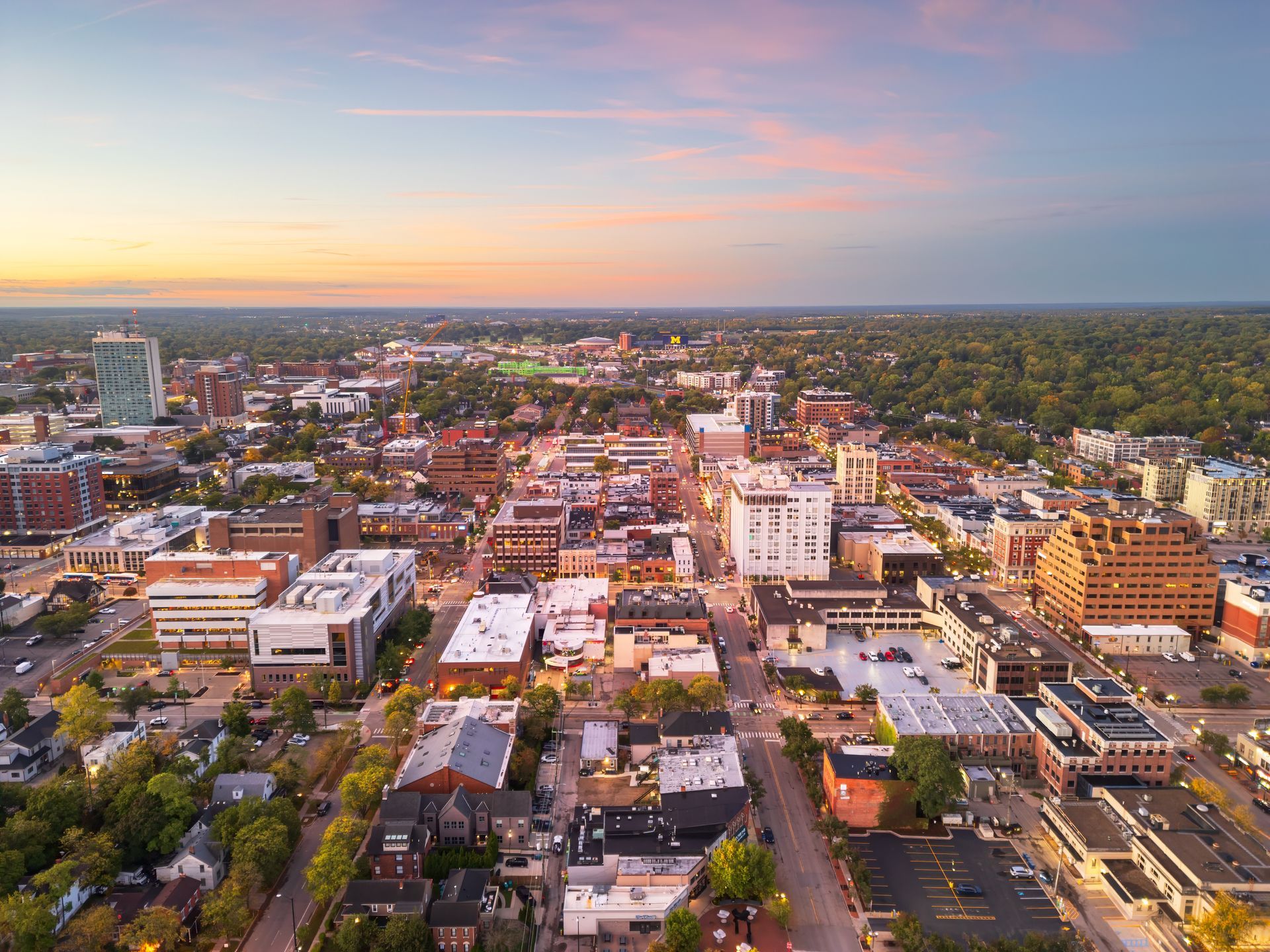 An aerial view of a city at sunset with lots of buildings and trees.