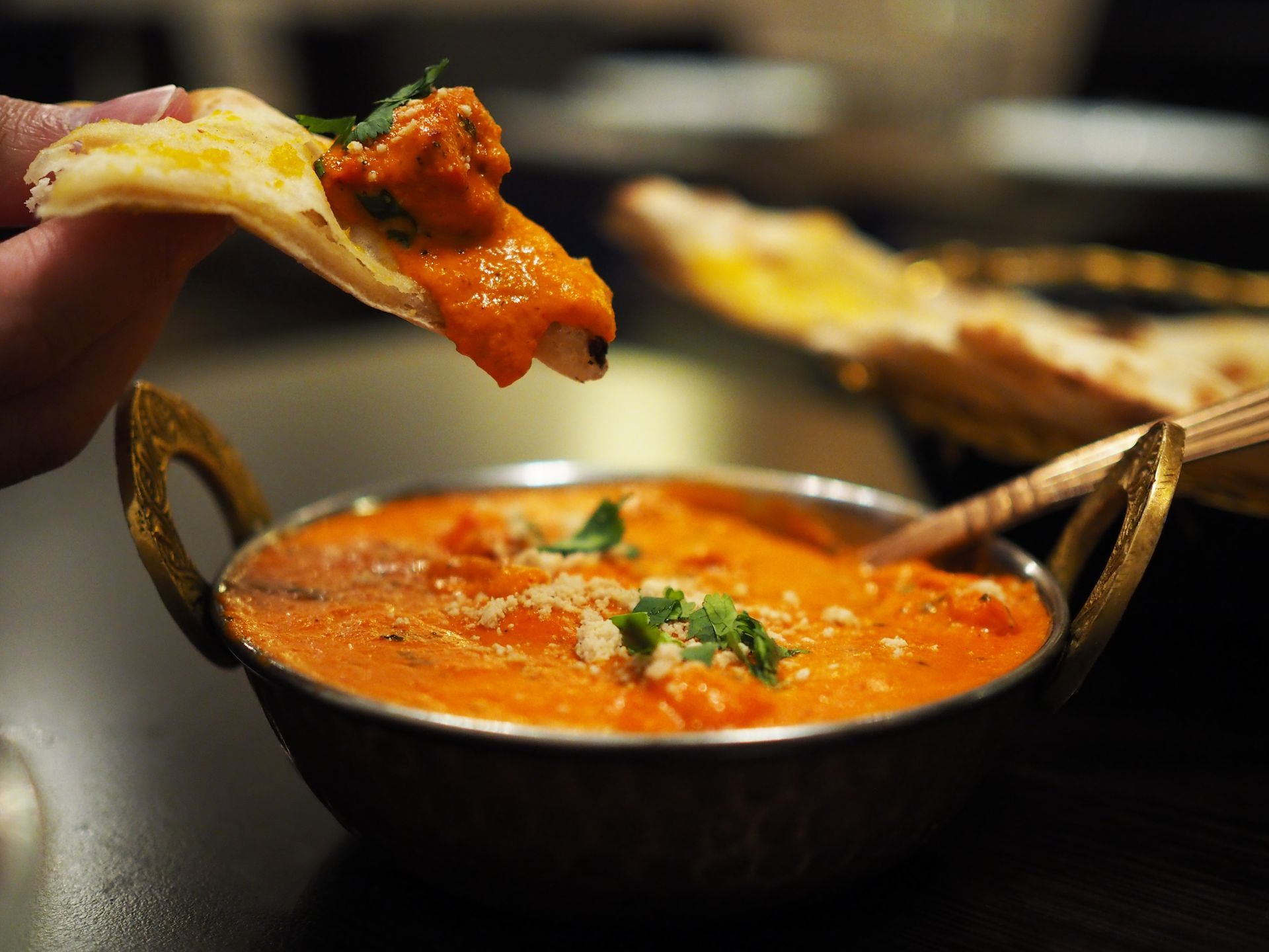 A person is dipping a piece of bread into a bowl of food.