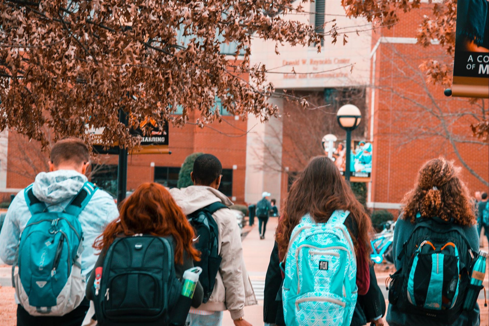 A group of students with backpacks are walking down a sidewalk.