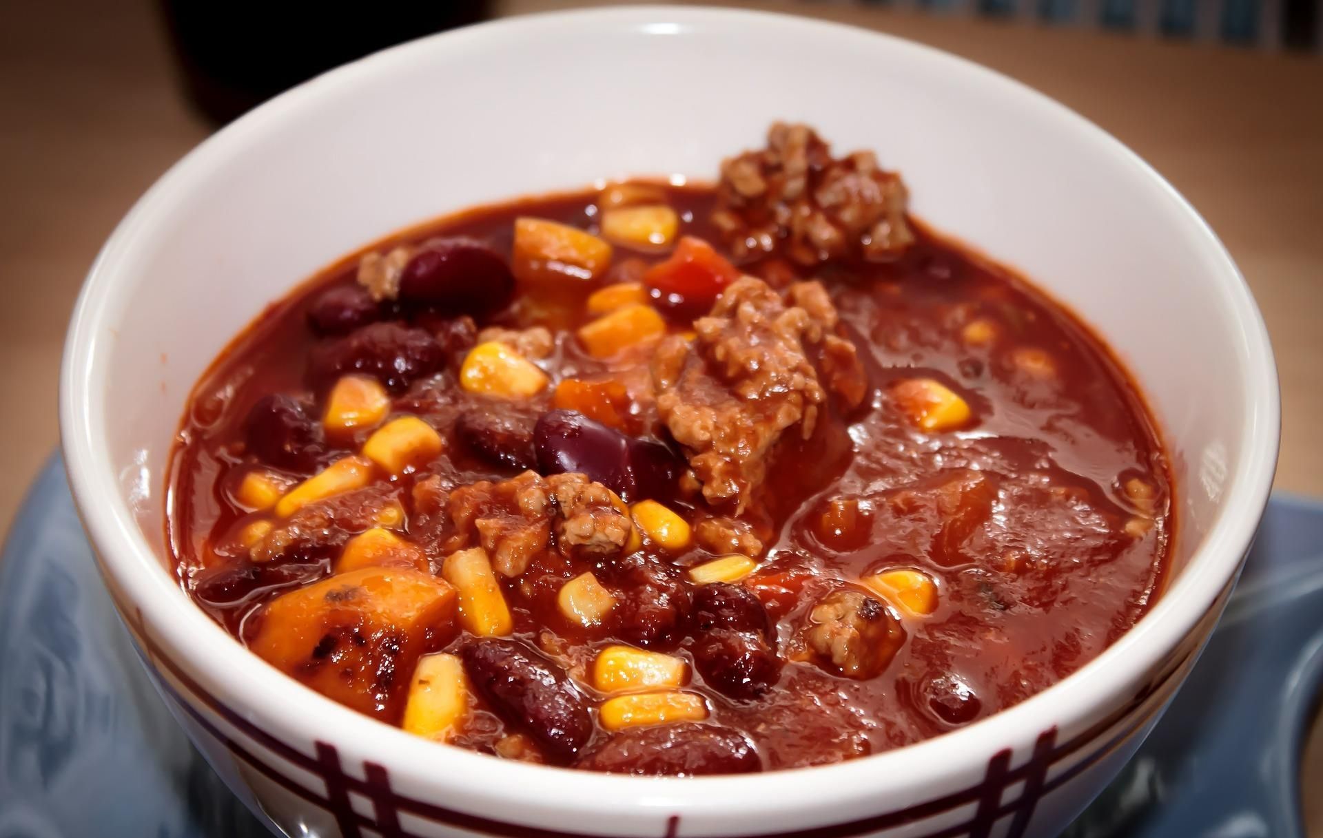 A bowl of chili with meat beans corn and carrots
