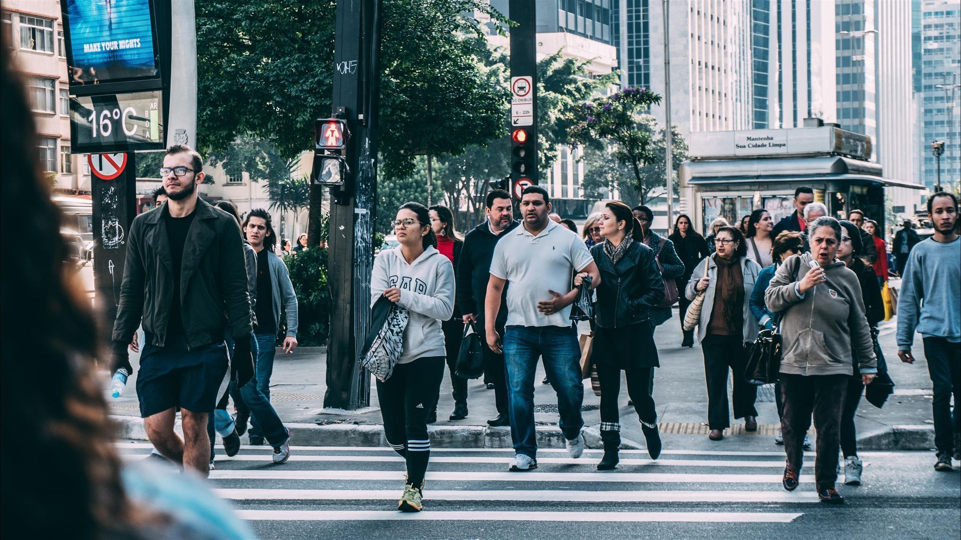 A large group of people are crossing a city street.