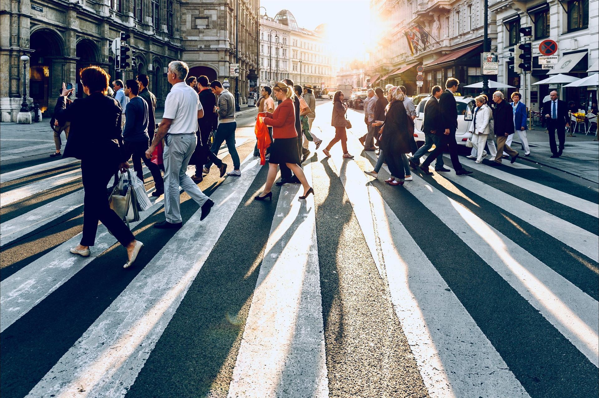 A large group of people are crossing a busy city street.