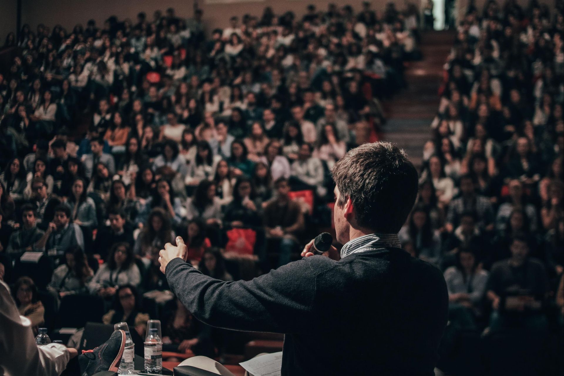 A man is giving a speech in front of a large crowd.
