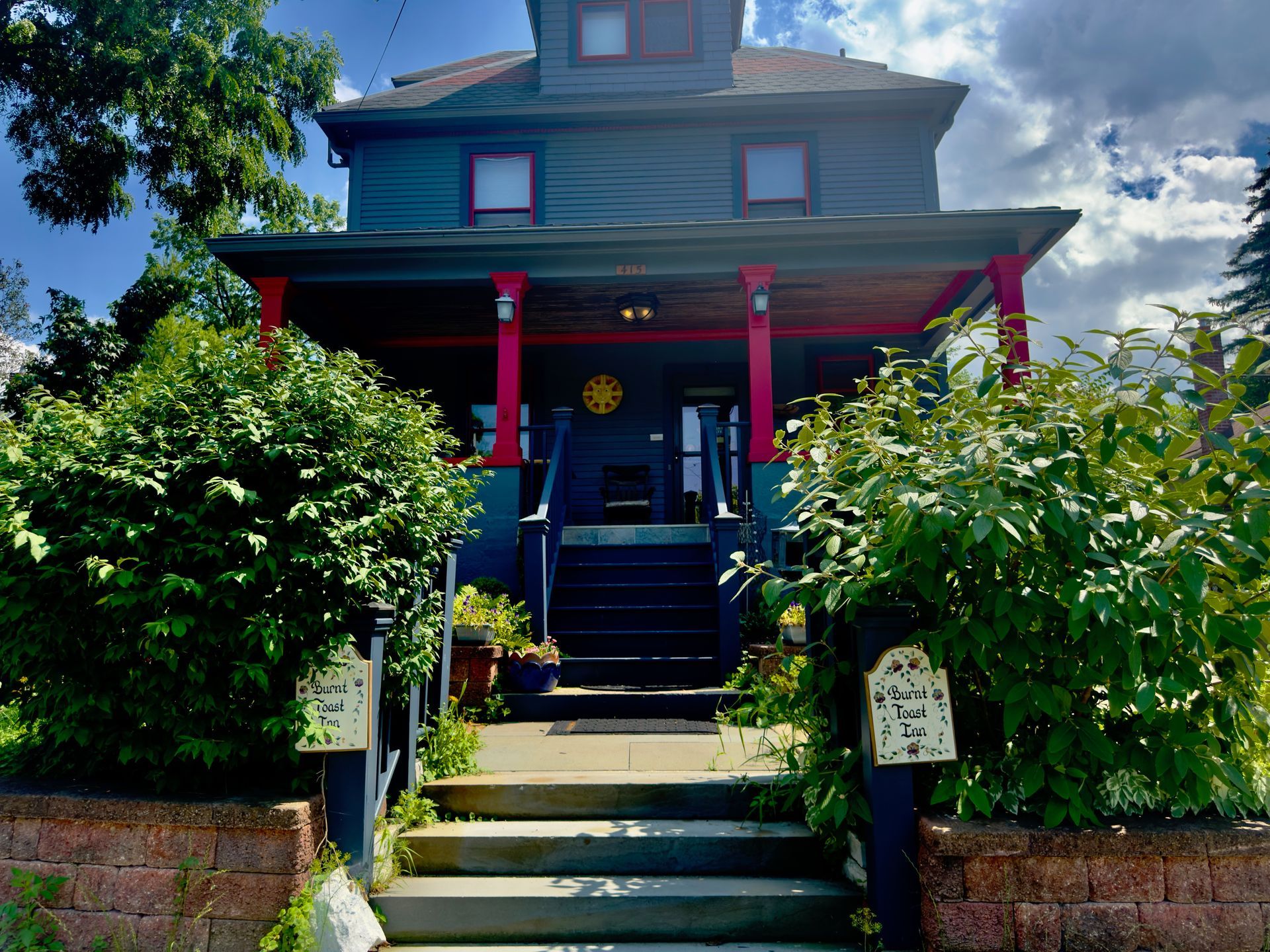 A blue house with a red porch and stairs