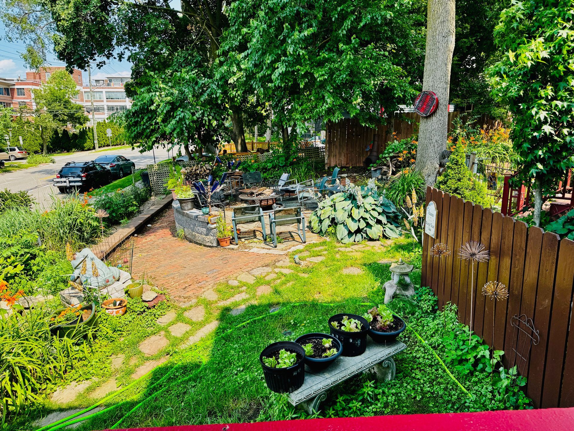 A garden with a wooden fence and a bench with potted plants on it.
