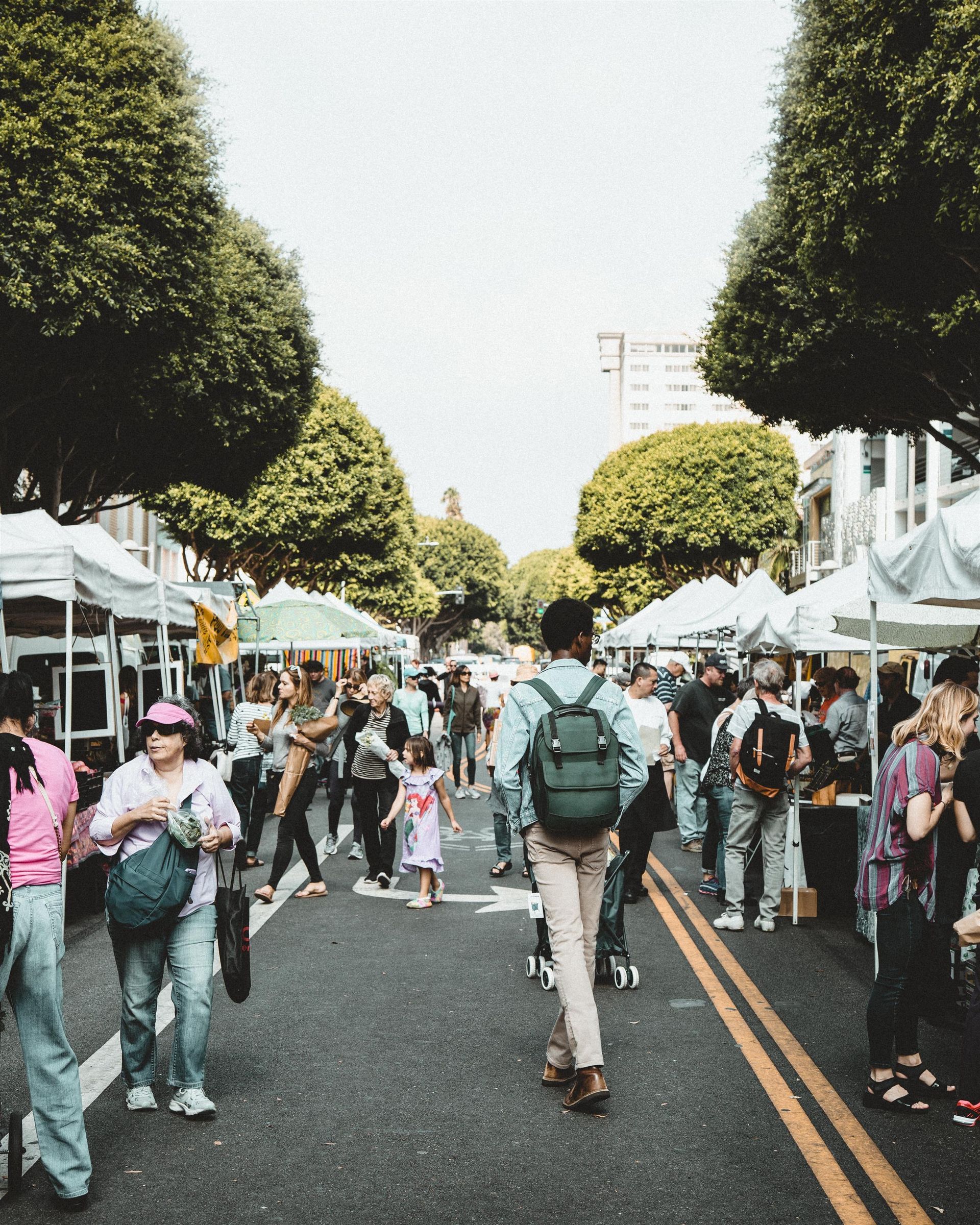 A man with a backpack is walking down a street filled with people