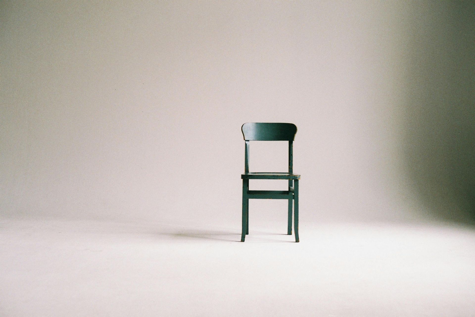 A black chair is sitting in the middle of a white room.