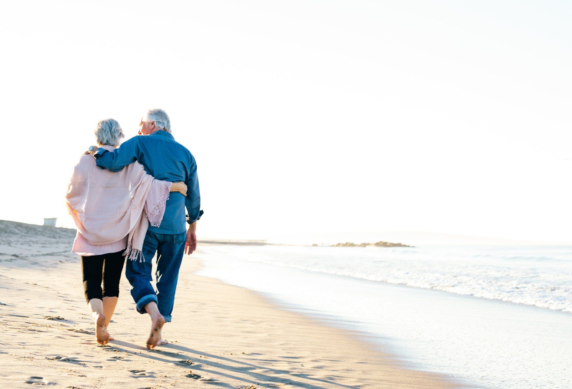 An old couple walking down the beach