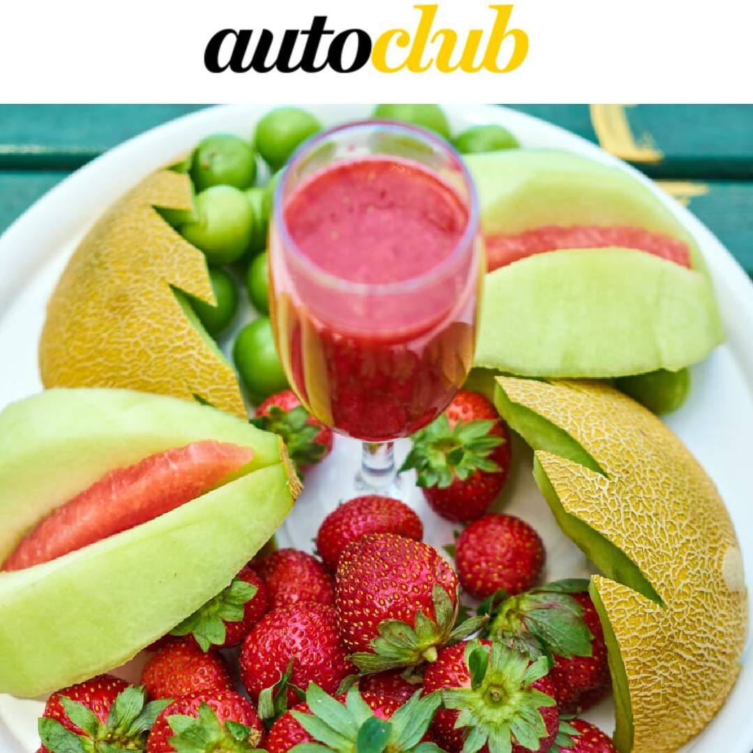 Plato de fruta, que incluye melón, fresas y ciruelas, con un vaso de batido rojo.