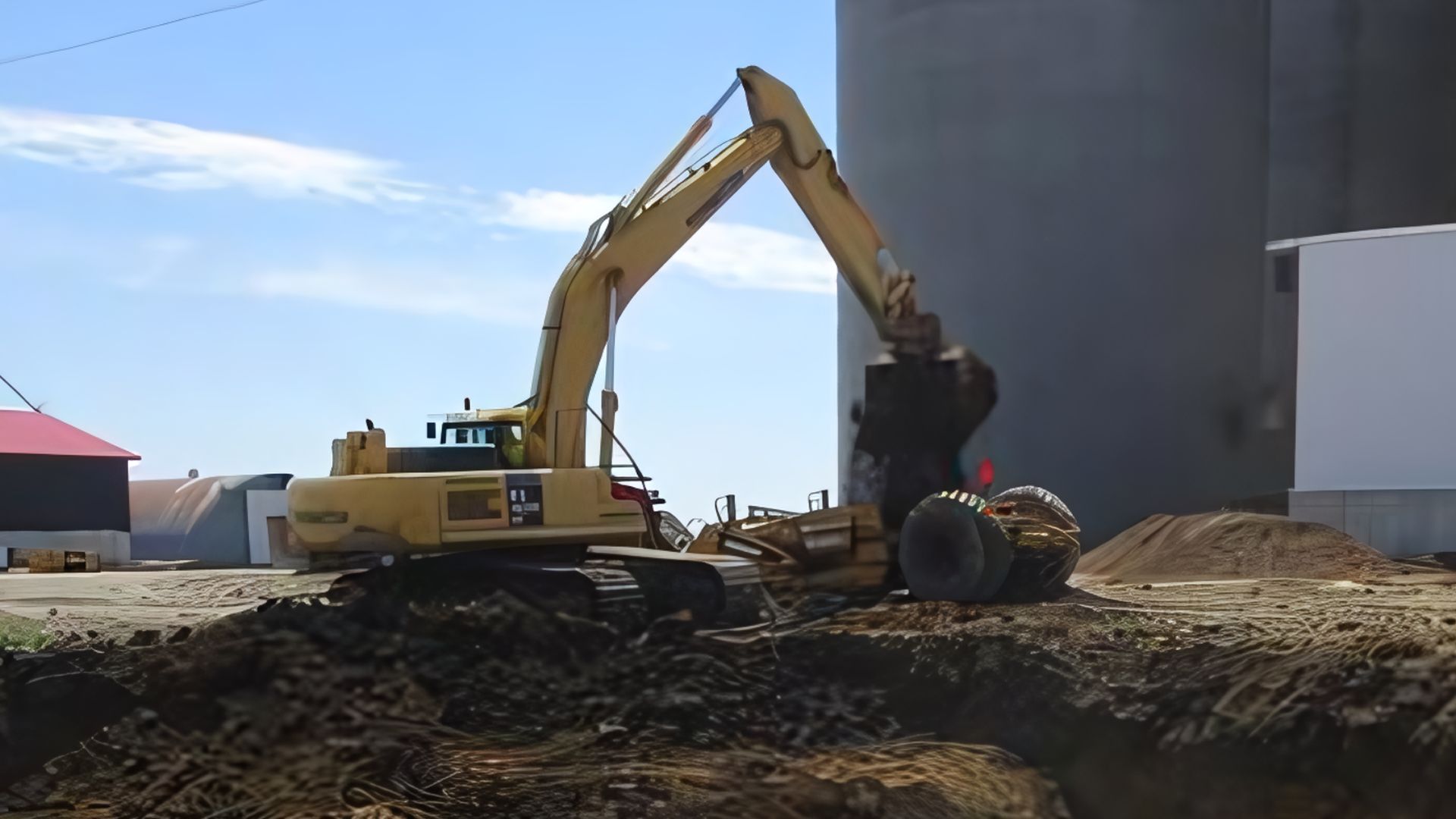 A large yellow excavator is digging a hole in the dirt
