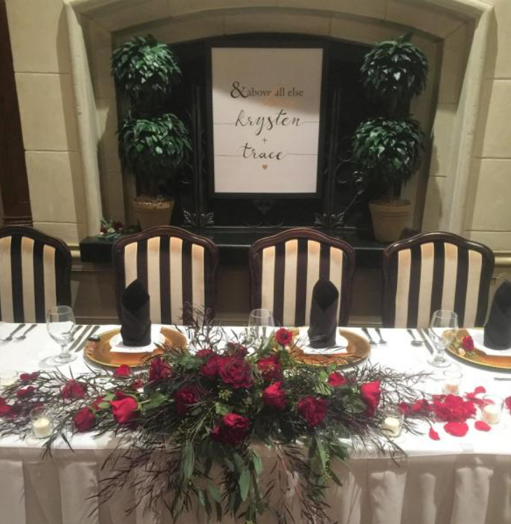Wedding reception table with floral centerpiece, black candles, and sign reading “Happily ever after”