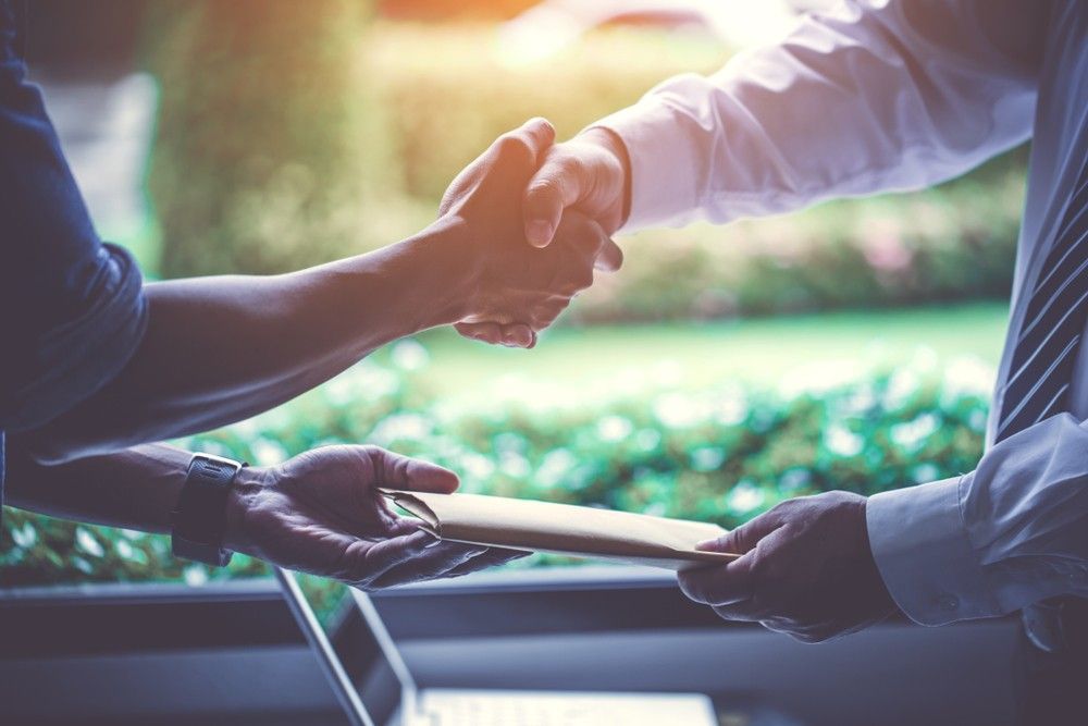 Two Men Are Shaking Hands Over a Piece of Paper — Loan Select Tablelands in Atherton, QLD