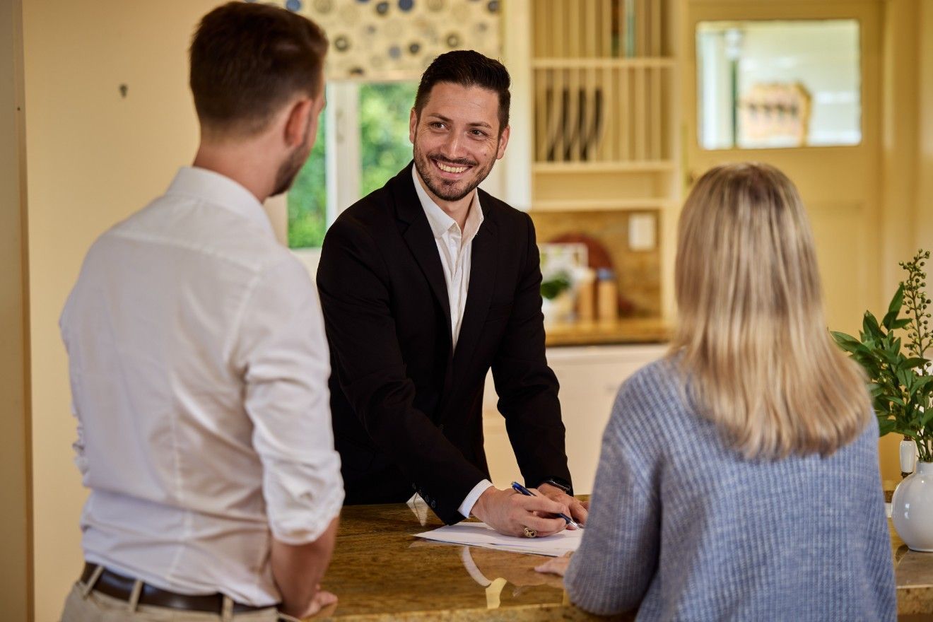 A Man in a Suit is Talking to Two People at a Counter — Loan Select Tablelands in Atherton, QLD
