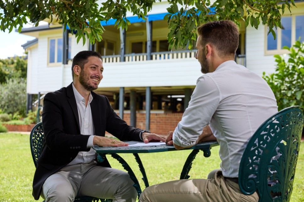 Two Men Are Sitting at a Table Talking to Each Other — Loan Select Tablelands in Atherton, QLD