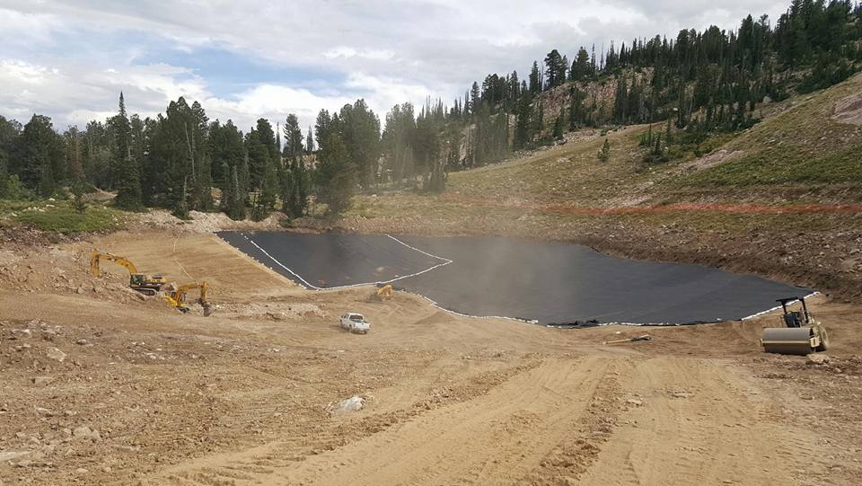 Pond liner in the mountains surrounded by trees and dirt