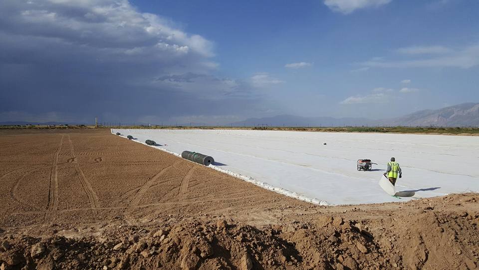 Large white surface with sand on the side.  Worker walking away from camera