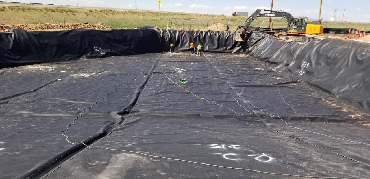 black liner inside a large pond-sized area with worker inside