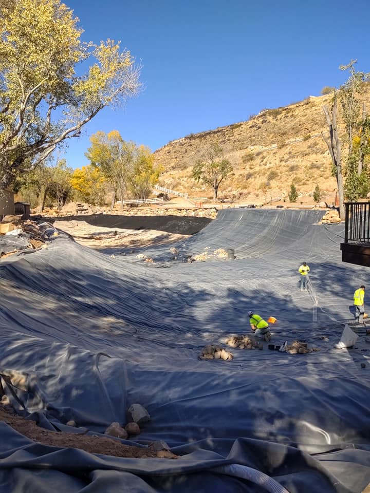 workers installing liner in desert -type area